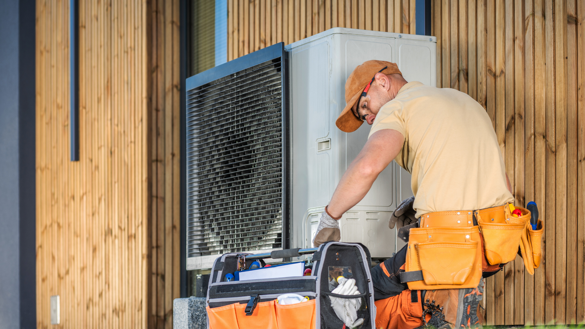 Contractor with a tool belt servicing an outdoor unit