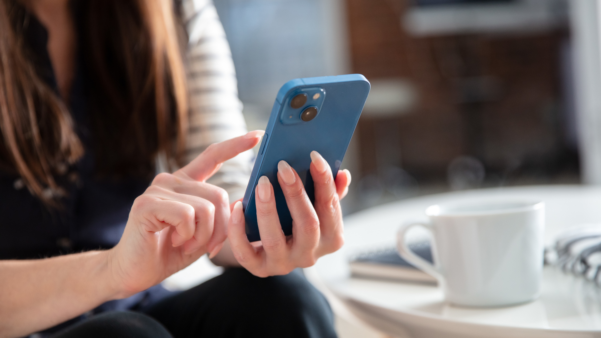 Homeowner texting on a phone at a kitchen table
